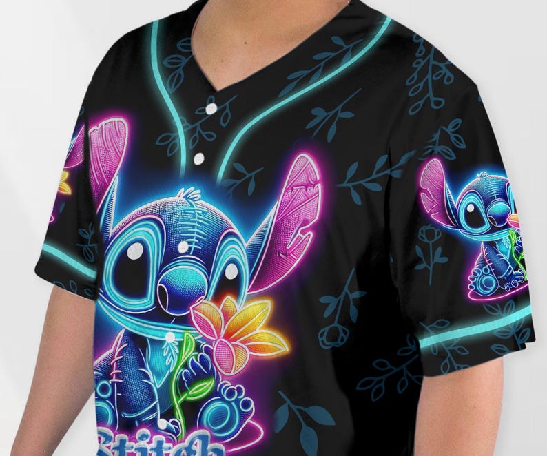 Puede incluir: Una camiseta de b&eacute;isbol negra con un gr&aacute;fico de Stitch en azul ne&oacute;n y rosa. El gr&aacute;fico muestra a Stitch sosteniendo una flor con el texto "Stitch" en la parte inferior.