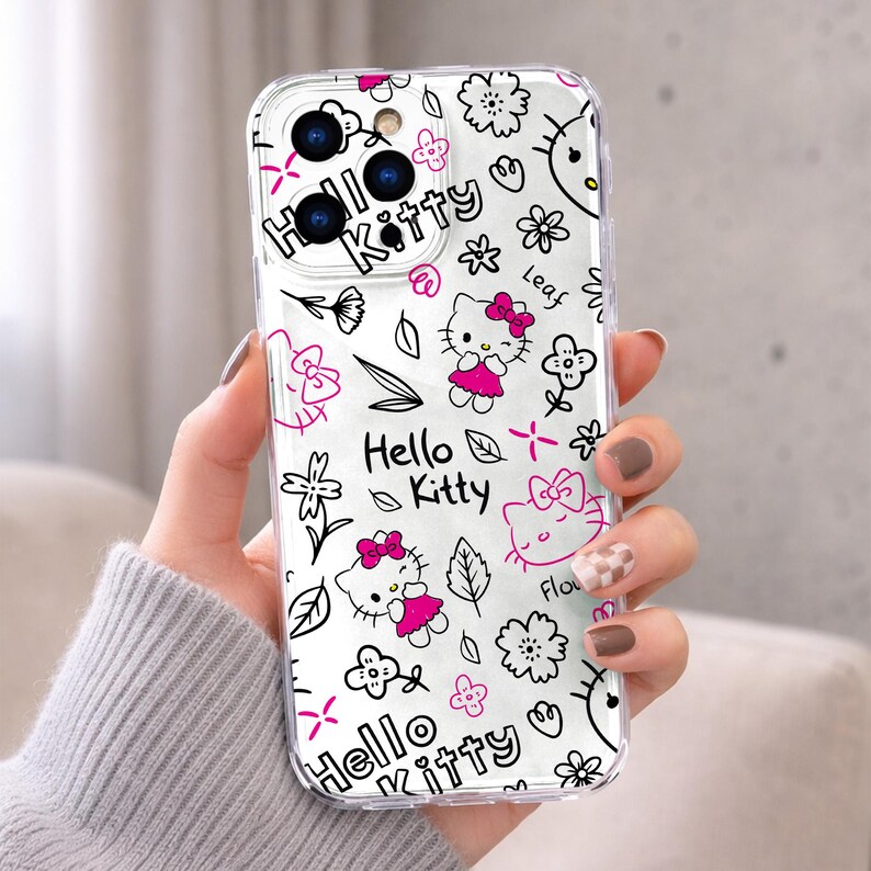May include: Clear phone case featuring a repeating pattern of Hello Kitty characters, flowers, and leaves in black and pink. The words "Hello Kitty" are also displayed. The case is designed to fit a smartphone.