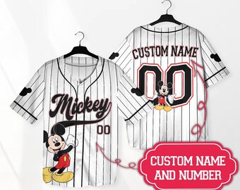 Può includere: Maglia da baseball bianca con design Mickey Mouse nero e rosso. La maglia ha un motivo a righe e dice "Mickey" in nero con contorno rosso. La maglia ha uno spazio per un nome e un numero personalizzati.