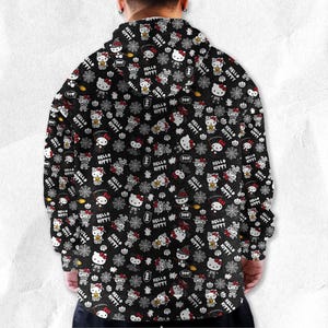 May include: Black hooded sweatshirt featuring a repeating pattern of Hello Kitty characters in Halloween costumes, spiders, and the words "Hello Kitty". The design includes white, red, and orange accents.