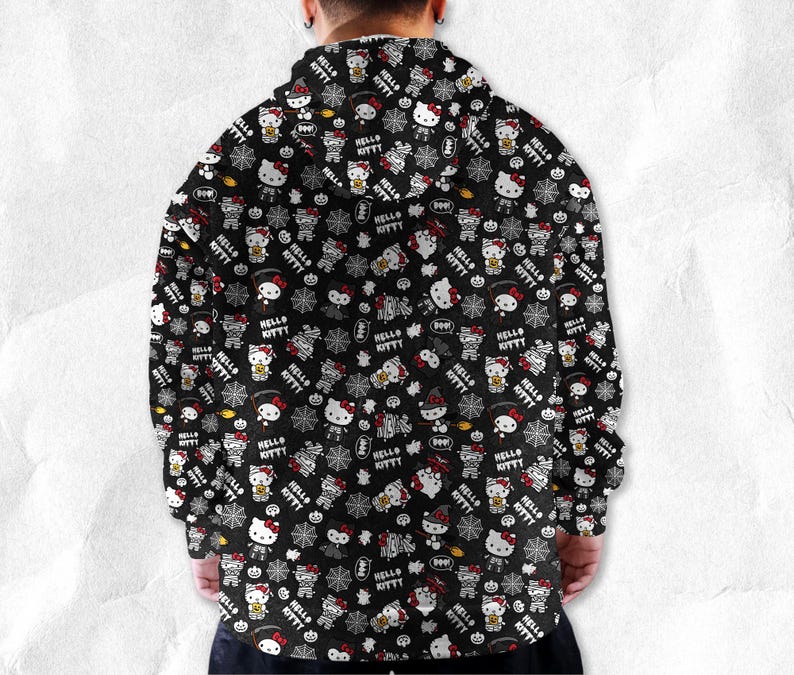 May include: Black hooded sweatshirt featuring a repeating pattern of Hello Kitty characters in Halloween costumes, spiders, and the words "Hello Kitty". The design includes white, red, and orange accents.