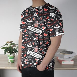May include: Black t-shirt featuring a repeating pattern of Hello Kitty characters, cupcakes, ice cream cones, and candies in red and white. The shirt includes the text "Hello Kitty" and "You have a way of brightening my day!"
