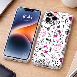 May include: Clear phone case with a white background featuring a Hello Kitty design in black and pink. The case has a clear border and is next to a phone with a digital display showing the time and date.