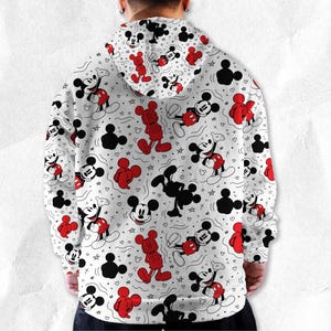 May include: White hoodie with a repeating pattern of Mickey Mouse in red, black, and white. The design includes Mickey Mouse figures in various poses, along with Mickey Mouse silhouettes, stars, and hearts. The hoodie has a drawstring hood.