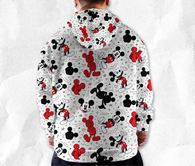 May include: White hoodie with a repeating pattern of Mickey Mouse in red, black, and white. The design includes Mickey Mouse figures in various poses, along with Mickey Mouse silhouettes, stars, and hearts. The hoodie has a drawstring hood.