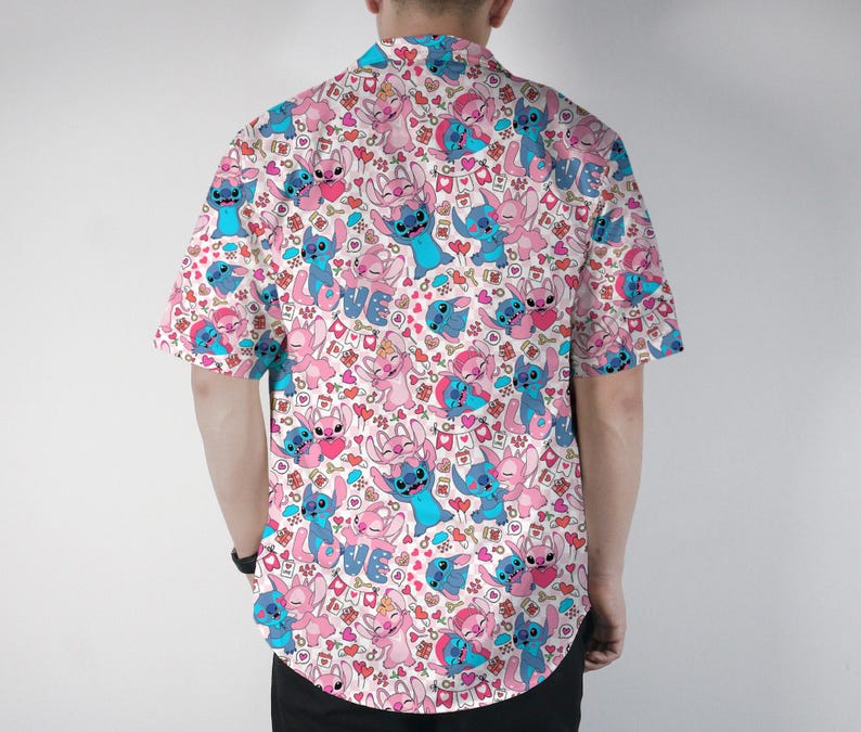 Puede incluir: Camisa de manga corta con un estampado repetido de personajes de dibujos animados azules y rosas, corazones y la palabra "LOVE" sobre un fondo blanco. La camisa est&aacute; hecha de tela ligera.
