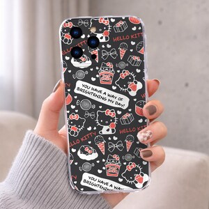 May include: A clear phone case featuring a repeating pattern of Hello Kitty characters, bows, ice cream cones, popcorn boxes, and candies in red and white on a black background. The case also has the text "YOU HAVE A WAY OF BRIGHTENING MY DAY!"