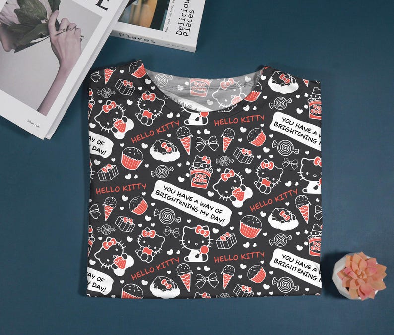 May include: Black t-shirt featuring a repeating pattern of Hello Kitty characters, cupcakes, ice cream cones, and bows in white and red. The shirt includes the text "Hello Kitty" and "You have a way of brightening my day!"