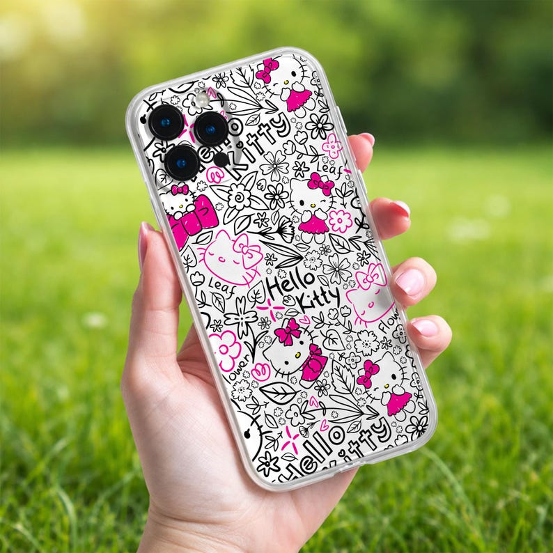 May include: Clear phone case featuring a black and white floral design with pink accents and Hello Kitty graphics. The case has a repeating pattern of flowers, leaves, and Hello Kitty characters. The text "Hello Kitty" is also visible.