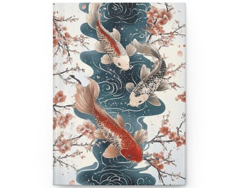 May include: A hardback journal featuring a watercolor illustration of three koi fish swimming in a blue stream. The fish are red, white, and black, with cherry blossom branches in the background. The cover has a white background.