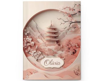 May include: A hardcover journal with a Japanese-inspired design. The cover features a pink pagoda, cherry blossoms, and mountains within a circular frame. The name "Olivia" is displayed in a decorative font.