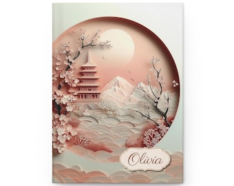 May include: A notebook with a Japanese-inspired design. The cover features a layered paper art scene with a pagoda, cherry blossoms, and a rising sun in shades of pink and white. The name "Olivia" is written on a decorative label.