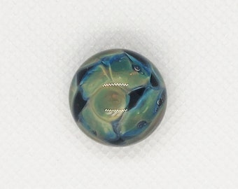 May include: A round, green, blue, and black glass marble with a swirling pattern.