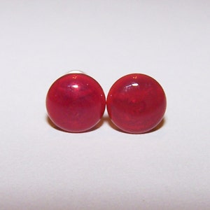 May include: A pair of red stud earrings with a shiny finish.