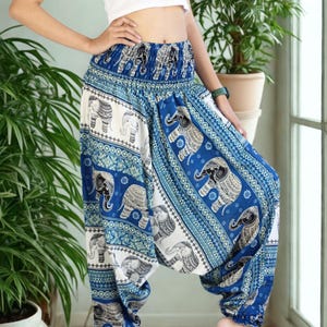 May include: Blue and white patterned harem pants with an elephant design. The pants have a wide elastic waistband and are gathered at the ankles. The fabric features a repeating pattern of elephants and geometric shapes.