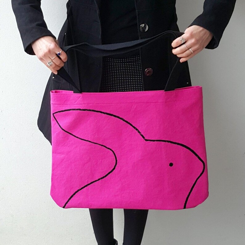 May include: A bright pink tote bag with a black outline of a rabbit on the front.