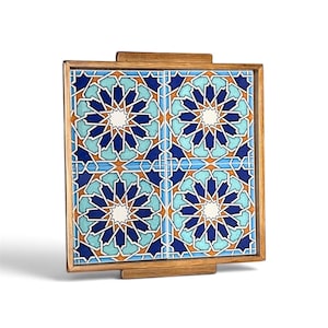 May include: A square wooden serving tray featuring four ceramic tiles with a geometric star pattern in shades of dark blue, light blue, and orange. The tray has a natural wood frame with small rectangular handles on the top and bottom edges.