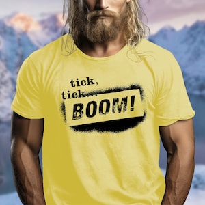 May include: A yellow t-shirt with black text that reads "tick, tick... BOOM!"