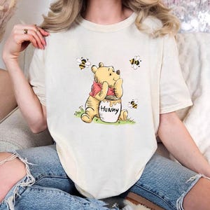 Camiseta de Winnie the Pooh con miel y abejas, linda camiseta rosa de dibujos animados con tarro de miel y abejas, suave camiseta unisex de regalo para fanáticos de Disney y amantes de la naturaleza.