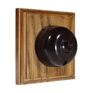 May include: A black Bakelite light switch with a round knob, mounted in a wooden frame.