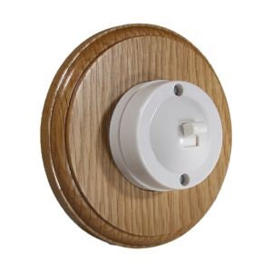 May include: A white ceramic light switch with a toggle switch, mounted on a round wooden plate.
