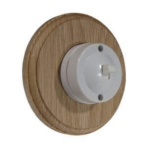 May include: A white ceramic light switch with a toggle switch, mounted on a round wooden plate.