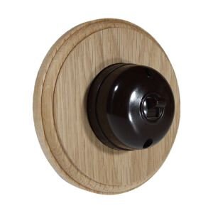 May include: A circular, light brown wooden wall plate with a dark brown, vintage-style light switch. The switch has a circular design with a central button. The wood grain is visible on the plate.