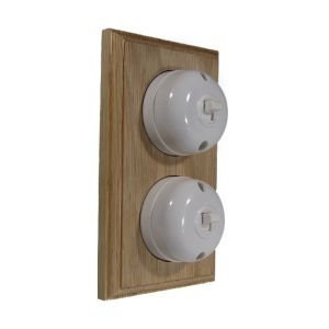 May include: A double light switch with a wooden frame. The switches are white porcelain with a round shape and a toggle switch.