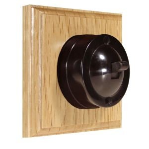 May include: A black bakelite light switch with a toggle switch, mounted on a light oak square wall plate.