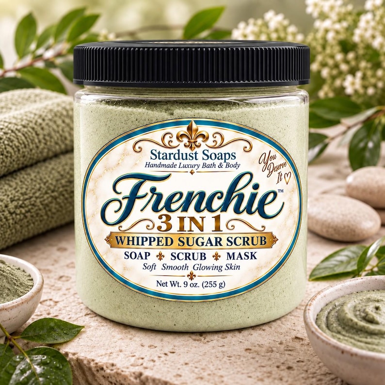 May include: A clear plastic jar with a black lid containing light green whipped sugar scrub. The label reads Stardust Soaps Frenchie 3 IN 1 WHIPPED SUGAR SCRUB SOAP SCRUB MASK Net Wt. 9 oz. (255 g) with decorative gold and blue accents.