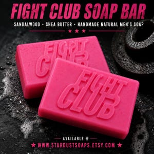 May include: Two rectangular pink soap bars embossed with the text FIGHT CLUB. The text FIGHT CLUB SOAP BAR, SANDALWOOD, SHEA BUTTER, HANDMADE NATURAL MEN'S SOAP, and the URL WWW.STARDUSTSOAPS.ETSY.COM are printed in white and pink on the image.