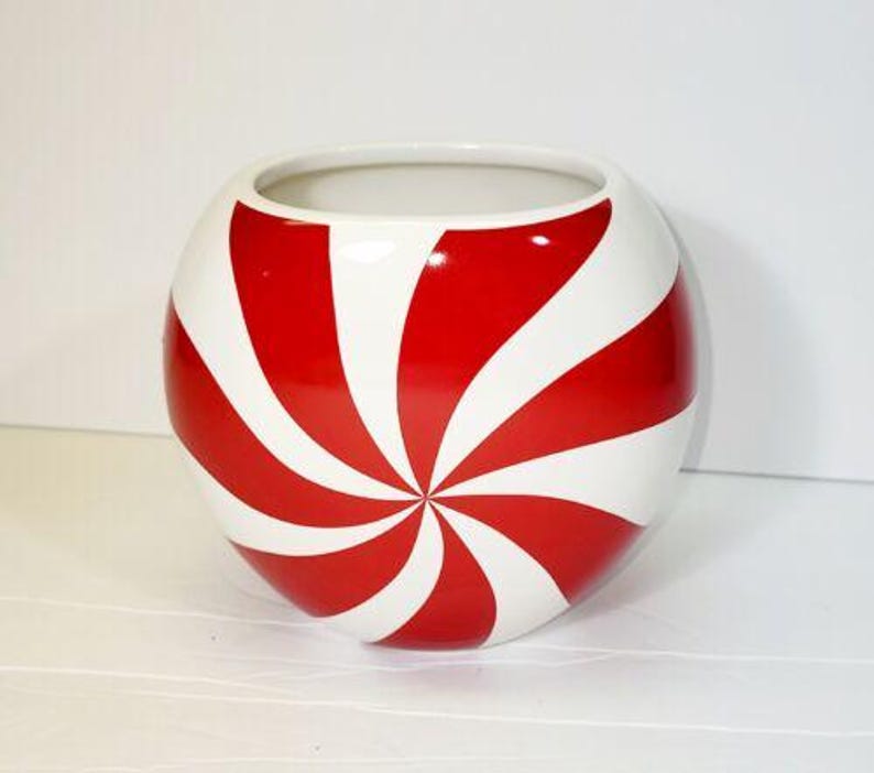 Pode incluir: Uma tigela redonda de cer&acirc;mica branca com um design espiral vermelho e branco. A tigela tem uma abertura larga e um acabamento brilhante. As listras vermelhas s&atilde;o espa&ccedil;adas uniformemente, criando um padr&atilde;o atraente. Esta tigela decorativa &eacute; adequada para v&aacute;rios usos.