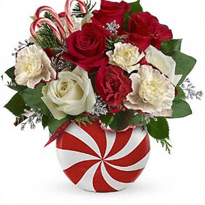 Pode incluir: Um arranjo floral festivo num vaso com riscas de menta. O buqu&ecirc; apresenta rosas vermelhas e brancas, cravos brancos, bengalas doces e elementos decorativos prateados. Uma pe&ccedil;a central com tema natalino.
