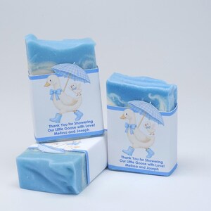 Blue silly goose baby shower soap favors displayed together, showing two wrapped handmade blue soap bars with goose design labels and one unwrapped soap on a clean white background