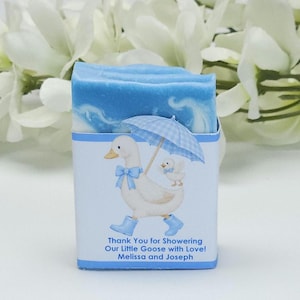 Blue silly goose baby shower soap favor featuring a handmade blue and white soap bar with a blue goose design label, personalized baby shower favor styled with white floral accents in the background