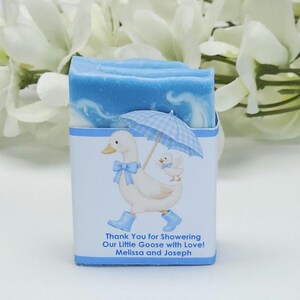 Blue silly goose baby shower soap favor featuring a handmade blue soap bar with a matching goose design label, styled with white floral accents in the background