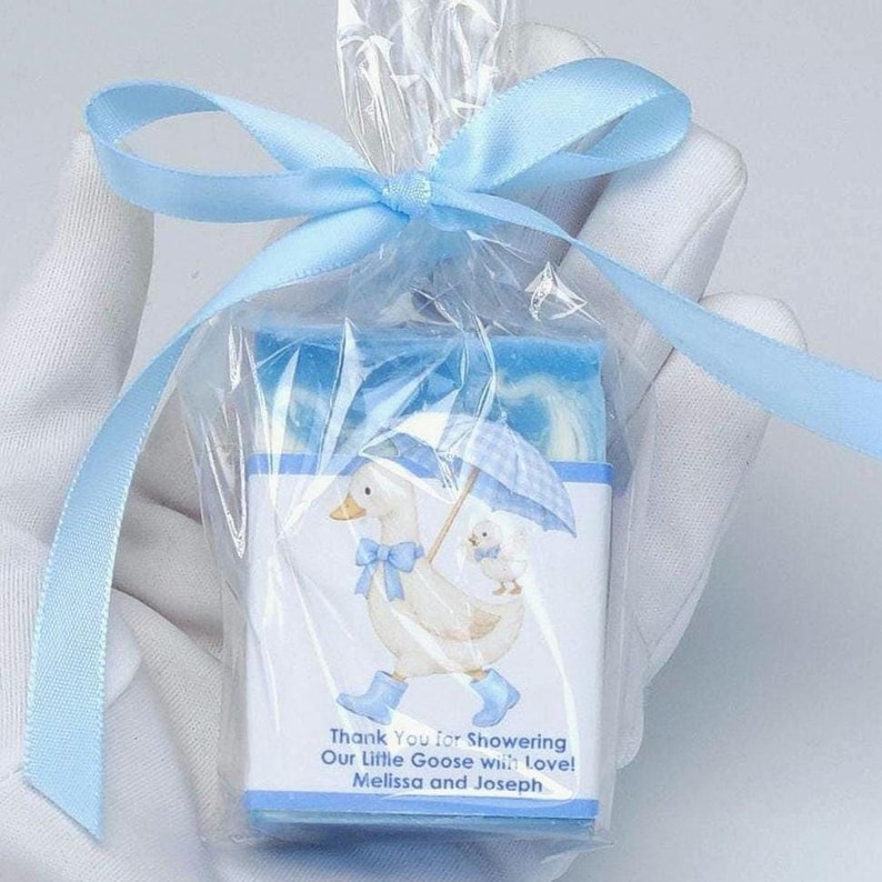 Blue silly goose baby shower soap favor wrapped in clear gift packaging with a soft blue ribbon, featuring a handmade blue soap bar and matching goose design label on a clean white background