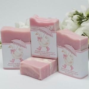 Pink silly goose baby shower soap favors displayed together, showing four handmade pink soap bars with matching goose design labels, styled with white floral accents in the background