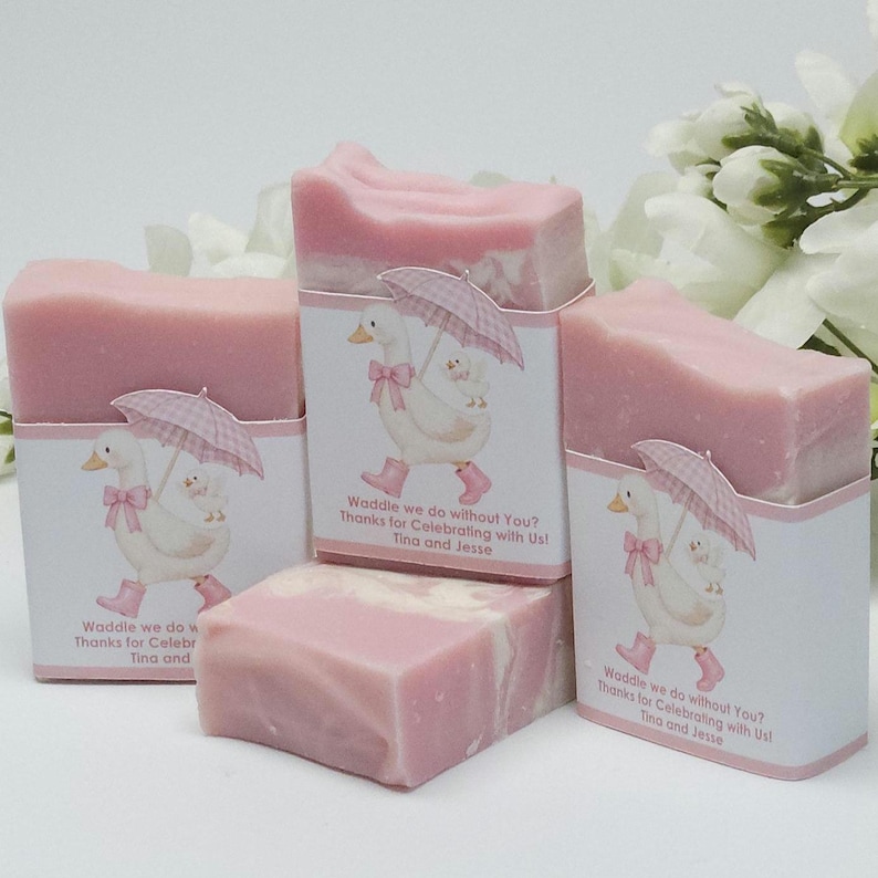Pink silly goose baby shower soap favors displayed together, showing four handmade pink soap bars with matching goose design labels, styled with white floral accents in the background