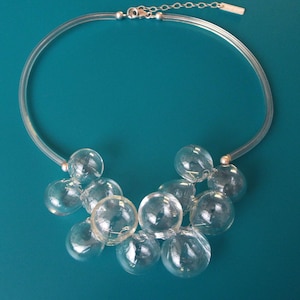 May include: A clear plastic necklace with a silver chain clasp and a cluster of clear glass bubble-shaped beads.