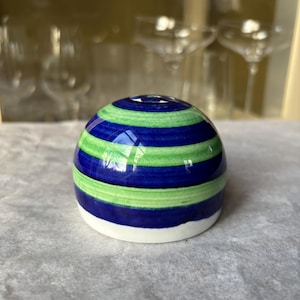 May include: A spherical ceramic bottle stopper. It has horizontal stripes in blue and green, with a white base. The design is simple and modern, suitable for various bottle types.