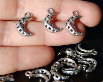 Puede incluir: Un grupo de dijes de metal plateado en forma de media luna con un diseño de celosía. Los dijes tienen un bucle en la parte superior para sujetarlos a joyas u otras manualidades.