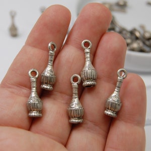 May include: Six silver charm pendants shaped like Italian wine bottles. The bottles have a woven design and are about 1 inch tall.