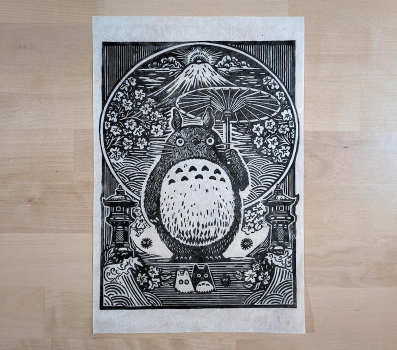 May include: Black and white woodcut print featuring a large, round creature holding an umbrella, with a mountain and cherry blossoms in the background. Two smaller creatures are at the bottom. Japanese-inspired art.