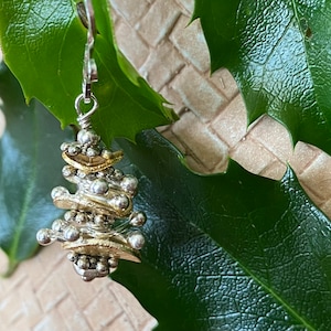 以下が含まれることがあります： 銀と金のトーンのぶら下がりイヤリング。小さなビーズと幾何学的な形を重ねたデザインです。