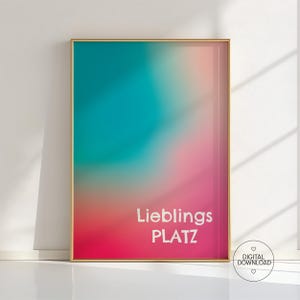 May include: A framed art print with a vibrant, abstract design. The artwork features a gradient of colors, including teal, pink, and coral. The words "Lieblings PLATZ" are displayed in white text. A digital download icon is in the lower right corner.