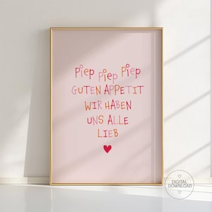 Könnte beinhalten: Ein gerahmter Druck mit hellrosa Hintergrund und goldenem Rahmen. Der Druck zeigt farbenfrohen Text im handschriftlichen Stil, darunter die Worte "Piep Piep Piep", "Guten Appetit", "Wir Haben", "Uns Alle" und "Lieb", sowie ein rotes Herz.