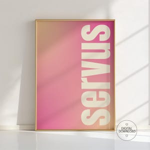 May include: A framed art print with a gradient background of pink and peach hues. The word "SERVUS" is printed vertically in a bold, off-white font. The frame is gold. A digital download icon is in the bottom right corner.