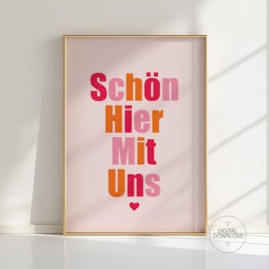 Könnte beinhalten: Gerahmter Kunstdruck mit den Worten "Schön Hier Mit Uns" in einem farbenfrohen, gestapelten Design. Der Text ist in Rosa-, Orange- und Rottönen gehalten, mit einem kleinen Herz am unteren Rand. Der Druck befindet sich in einem goldenen Rahmen.