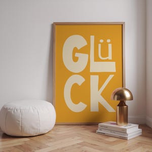 Gelbes Typografie Poster mit dem Wort „Glück“. Modernes Wandbild für Wohnzimmer, Küche oder Büro. Strahlt Motivation, Energie und Positivität aus – perfekt als Geschenk oder Deko für Zuhause und Familie.